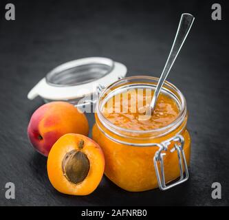 Partie de confiture d'abricots sur une dalle d'ardoise rustique (selective focus ; close-up shot) Banque D'Images