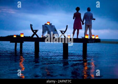 Couple romantiquement bénéficiant d'un coucher de soleil sur la jetée. Banque D'Images