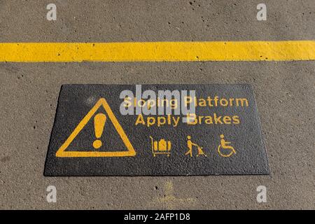 Avis informant les usagers du rail pour appliquer les freins de roues automoteurs équipements pour la sécurité sur le bord de la plate-forme en pente à Newton Abbot, Devon. Banque D'Images