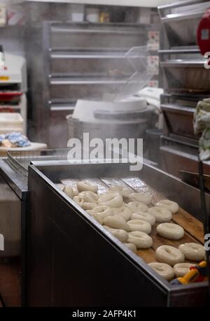 Les bagels en cours à une boulangerie traditionnelle juive dans Brick Lane, East London, UK. Bagels sont traditionnellement bouillir brièvement avant qu'ils sont cuits. Banque D'Images