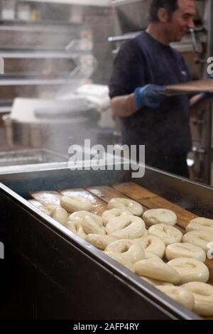 Les bagels en cours à une boulangerie traditionnelle juive dans Brick Lane, East London, UK. Bagels sont traditionnellement bouillir brièvement avant qu'ils sont cuits. Banque D'Images