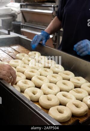 Les bagels en cours à une boulangerie traditionnelle juive dans Brick Lane, East London, UK. Bagels sont traditionnellement bouillir brièvement avant qu'ils sont cuits. Banque D'Images