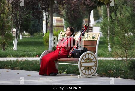 Jeune étudiant se reposant sur un banc de parc à Achgabat Banque D'Images