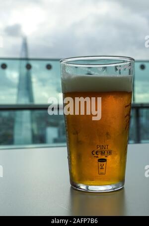 Une pinte de bière sur la table avec le Shard gratte-ciel en arrière-plan Banque D'Images
