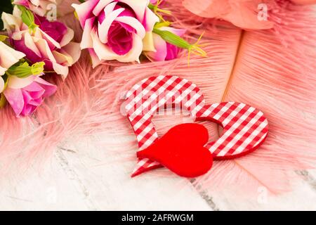 Valentine décoration avec coeur rouge et rose roses sur plumes de fond. Banque D'Images