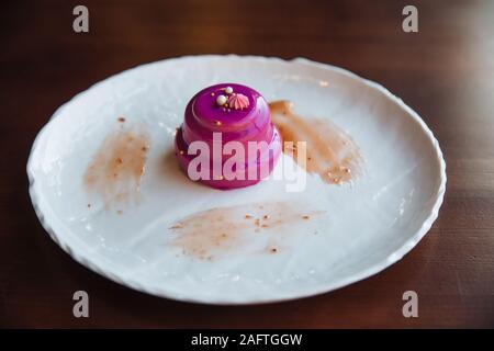 Gâteau avec glaçage rose coulé de remplissage en noyer. Sur une assiette blanche, debout sur la table. Banque D'Images