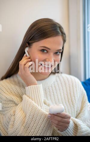 Cute femme agréable de mettre un écouteur Banque D'Images