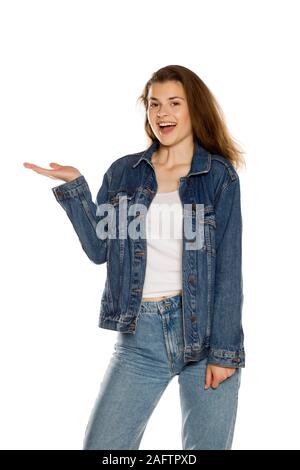 Belle jeune femme en jeans holding objet imaginaire sur sa main sur fond blanc Banque D'Images