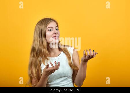 Jeune femme blonde choqué étend les mains, semblant confus sur orange wall Banque D'Images