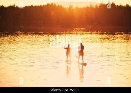 Standup paddleboarding couple Silhouette par beau coucher du soleil, le lac Shawnigan Lake, Canada Banque D'Images