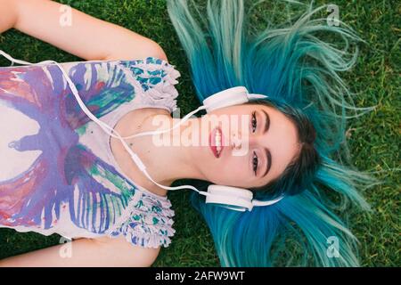 Portrait jeune femme avec les cheveux bleus d'écouter de la musique avec des écouteurs Banque D'Images