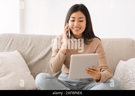 Girl le multitâche, l'aide de comprimés et en parlant au téléphone Banque D'Images