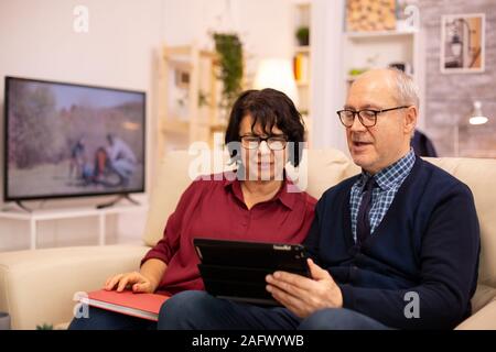Beau vieux couple à l'aide d'une tablette numérique pour discuter avec leur famille. Les personnes âgées à l'aide de la technologie moderne Banque D'Images