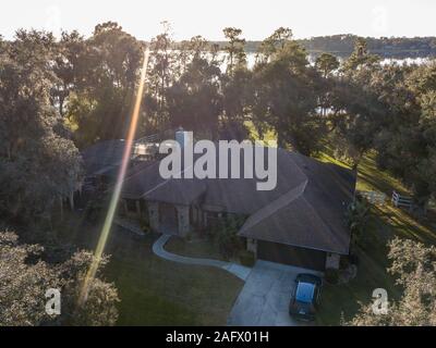 Photographie aérienne d'une maison entourée d'arbres avec le soleil brillant en arrière-plan Banque D'Images