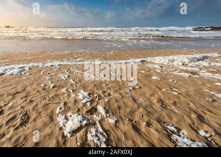 Spume ou sea foam à gauche sur la plage de Fistral par temps venteux à Newquay en Cornouailles. Banque D'Images