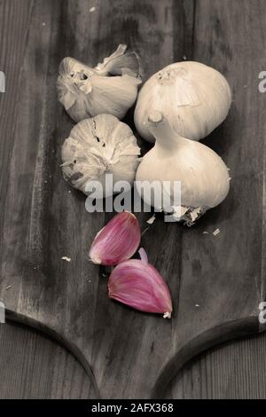 Tête d'ail et de girofle sur une planche à découper en bois. Avec l'harmonisation des couleurs et couleur sélective Banque D'Images
