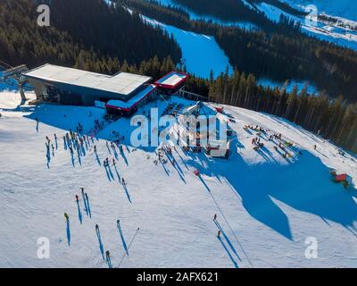 Station de ski par temps ensoleillé. La neige sur les pistes d'une montagne boisée. Beaucoup de touristes près de la station de ski et d'un café. Vue aérienne Banque D'Images