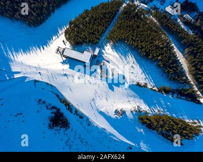 Station de ski par temps ensoleillé. Pente de ski d'une montagne boisée. Beaucoup de touristes près de la station de ski et d'un café. Vue aérienne Banque D'Images