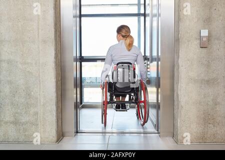 Businesswoman dans un fauteuil roulant avec l'ascenseur de l'entreprise La société Banque D'Images