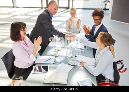 Businessman giving bidirectionnel pour business woman in wheelchair in a meeting Banque D'Images