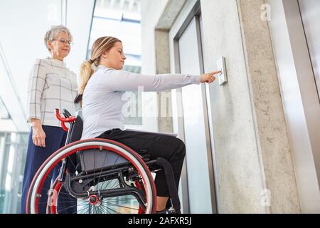 Jeune femme dans un fauteuil roulant appuie sur un bouton sur l'ascenseur pour l'inclusion concept Banque D'Images