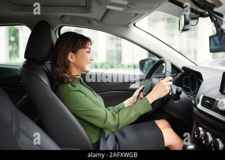 Conduire autour de la ville. Young attractive woman smiling et à tout droit en conduisant une voiture Banque D'Images