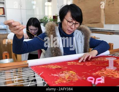 (191217) -- BEIJING, le 17 décembre 2019 (Xinhua) -- Beijing Yu Jing, un artiste, broderie Broderie n sur un tissu à son atelier à Beijing, capitale de Chine, le 11 décembre 2019. Yu Jing, qui a fait des broderies de Beijing depuis 2004, a créé un atelier de broderie de Beijing avec certains de ses amis artistes, il y a deux ans, dans l'espoir d'ajouter quelques éléments modernes à cet artisanat traditionnel chinois. Broderie de Beijing, également connu sous le nom de broderie impériale, est connu comme l'un des huit artisanat exquis de Beijing. (Xinhua/Ren Chao) Banque D'Images