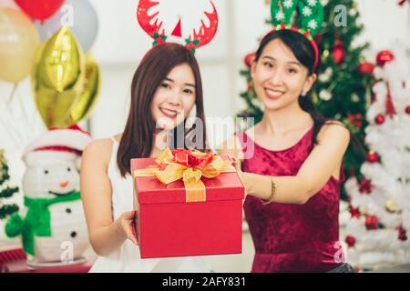 Deux filles asiatiques de l'adolescence dans le bonheur Noël Nouvel an instant cellebration donne la boîte-cadeau. Banque D'Images