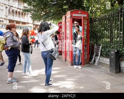 Pour les touristes visitant Londres en prenant un instantané de leur visite à l'aide d'un téléphone rouge traditionnel fort comme une identification de l'emplacement. Banque D'Images