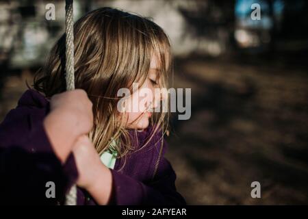Visage de jeune fille en hiver la lumière du soleil sur le swing à l'extérieur Banque D'Images