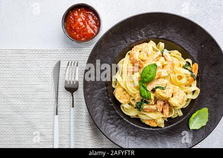 Les pâtes italiennes Les pâtes dans une sauce crémeuse aux crevettes sur une plaque noire, vue du dessus Banque D'Images