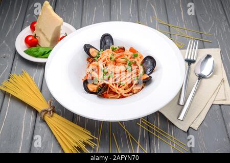 Pâtes aux moules et crevettes, sauce tomate, basilic et parmesan râpé sur fond de bois rustique Banque D'Images