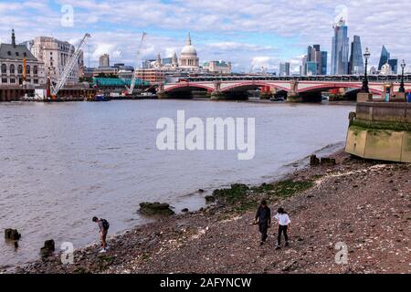 Les gens marchent le long de la Tamise comme la marée est out, la Cathédrale St Paul et les toits de Londres derrière eux, London, UK Banque D'Images