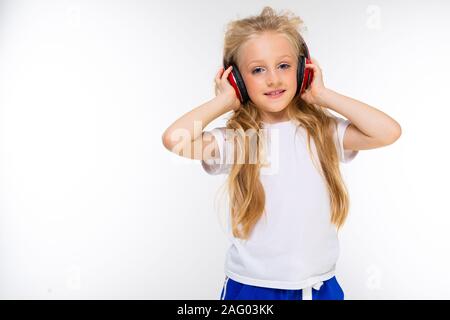 Sports adolescentes dans le sport à faire écouter de la musique avec de grands écouteurs isolé sur fond rouge Banque D'Images