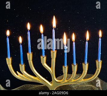 La menorah d'or avec 9 bougies bleu indiquant les huit flammes et la neuvième flamme à l'aide d'un esclave noir fond mousseux Banque D'Images