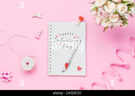 Ordinateur portable maquette sur fond rose avec Happy valentines day, bouquet de roses, Handy Craft et stylo. Des maquettes de design élégant avec espace pour texte. Banque D'Images