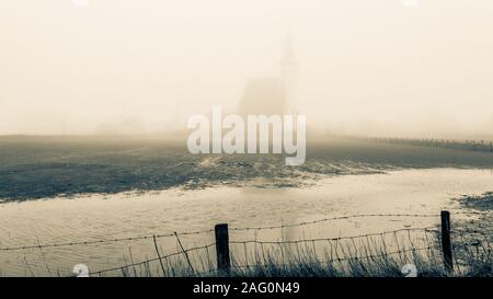 Matin brumeux d'automne, l'église de Den Hoorn derrière les barbelés. L'île de Texel aux Pays-Bas, photo teinté Banque D'Images