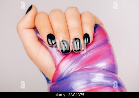 Avec les mains manucure noir tenant dans slime bleu et rose couleurs vibrantes Banque D'Images