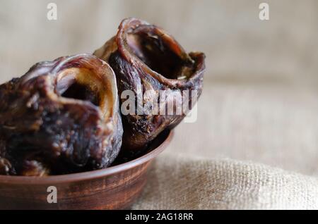Close-up de friandises préférés. Gâteries pour chiens savoureux dans une cuvette d'argile. Bœuf séché du larynx. Vue de côté. Focus sélectif. Photo paysage arrangement. Banque D'Images
