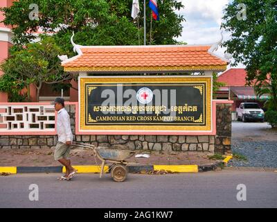 Un travailleur avec une brouette passe le signe extérieur de la Direction générale de Kampot de la Croix-Rouge cambodgienne Banque D'Images