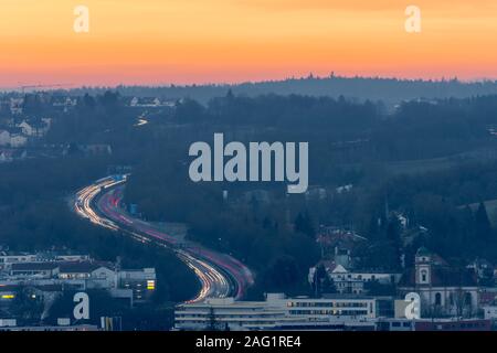 Des voitures en mouvement dans un fort trafic sur autoroute allemande à travers la ville de Ratisbonne pendant le lever du soleil d'hiver coloré Banque D'Images