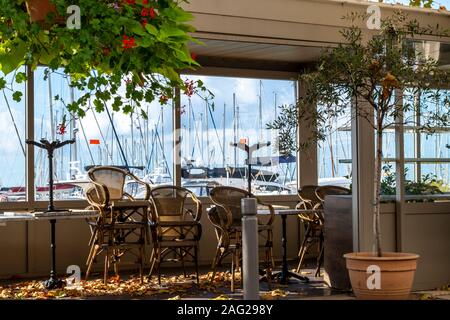 Un petit vide, terrasse couverte avec tables et chaises empilées se remplit de feuilles à la Plaisance de Cannes, en France, comme l'automne commence sur la côte d'Azur Banque D'Images