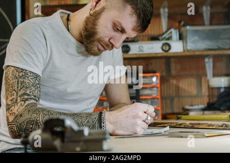L'artiste artisan créateur d'un nouveau produit en bois dans son atelier à domicile. L'homme au travail sur bois concept Banque D'Images