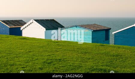 Cabines de plage en bois de couleur face à l'océan calme. Whitstable Kent en Grande-Bretagne Banque D'Images