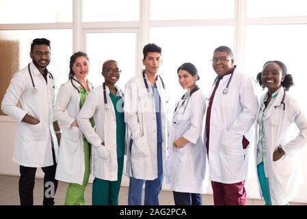 Les étudiants en médecine, médecins, race mixte. Une équipe de jeunes gens en blouse blanche posant dans le couloir de l'hôpital Banque D'Images