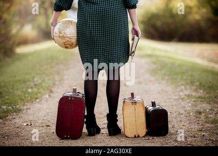 Femme se tenant sur une route vide près de sa valise pendant tenir la bible et un globe Banque D'Images