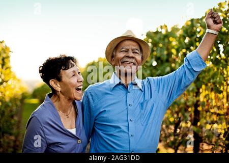 Très happy senior couple marchant à travers le vignoble. Banque D'Images