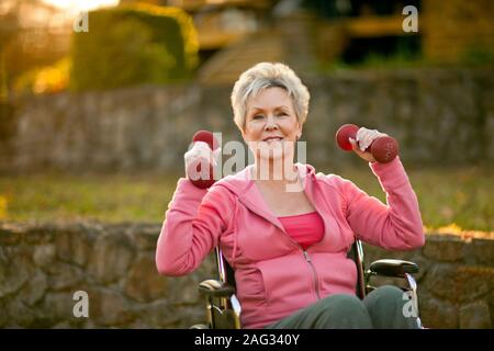Portrait of a young woman lifting-haltères en position assise, dans un fauteuil roulant. Banque D'Images