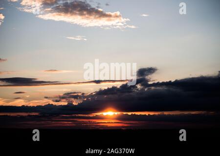 Paysage à couper le souffle du soleil se cachant derrière les nuages pendant coucher de soleil Banque D'Images