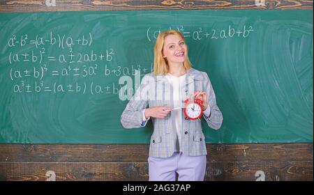 Enseignant femme tenir réveil. Elle se soucie de la discipline. Le temps d'étudier. Enseignants bienvenue année scolaire. À compléter la main-d'œuvre qualifiée enseignante engagée aux éducateurs. La discipline scolaire concept. Banque D'Images